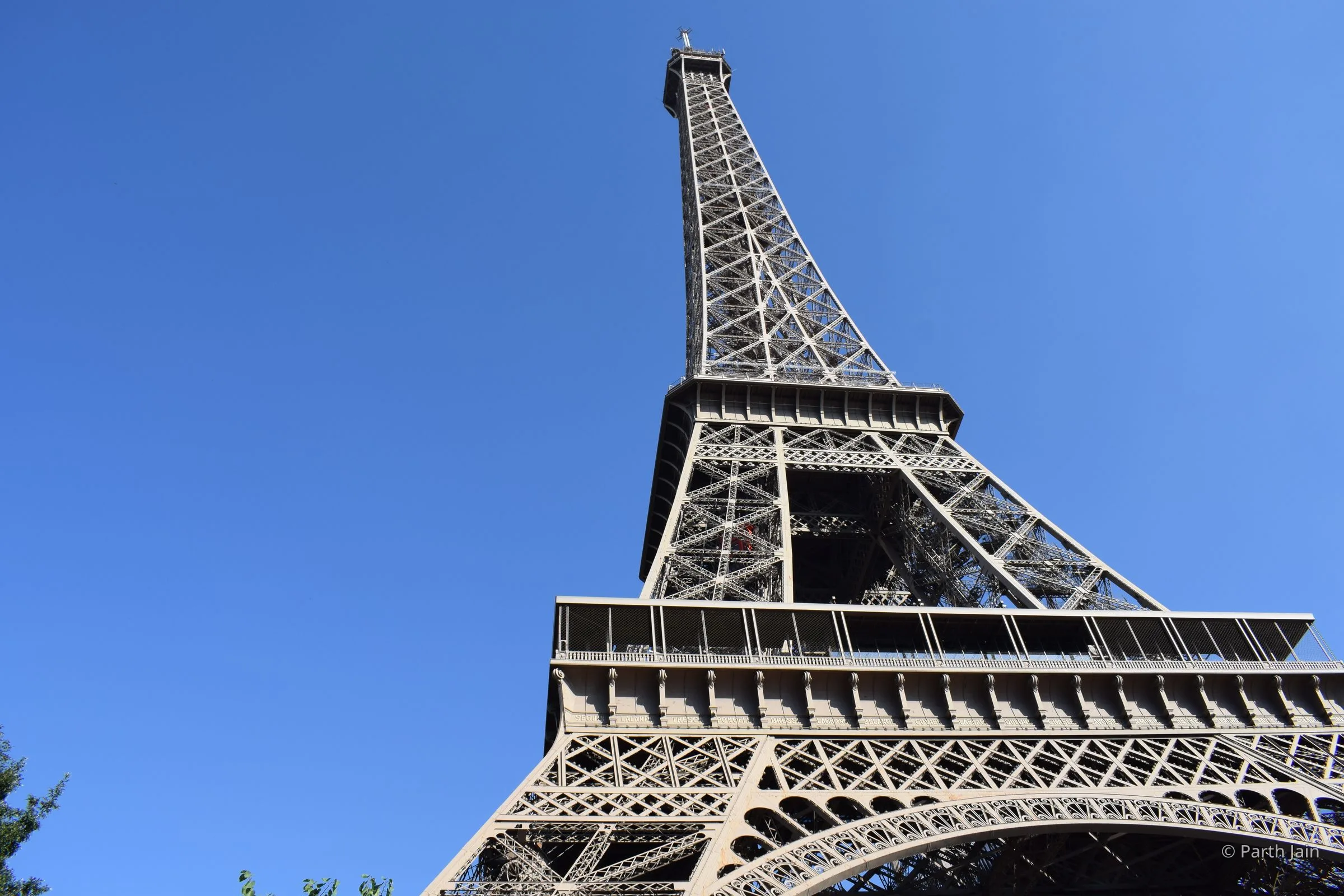 The Eiffel Tower seen from directly beneath, looking up the south leg into clear blue sky.